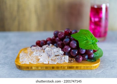 Refreshing A Glass Of Purple Grape Juice With Ice Cubes On Wooden Tray