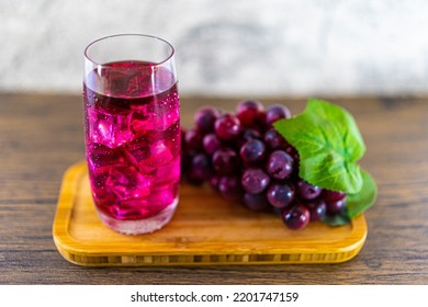 Refreshing A Glass Of Purple Grape Juice With Ice Cubes On Wooden Tray