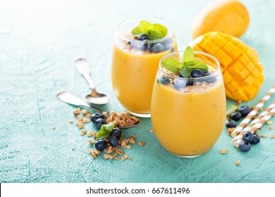 Refreshing and healthy mango smoothie with granola and fresh blueberries