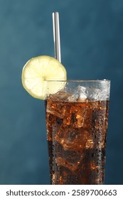 Refreshing iced cola with lime slice on blue background, closeup