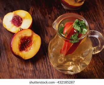 Refreshing iced green tea with peaches and mint, served in a glass with ice cubes and brown sugar on rustic wooden board, selective focus