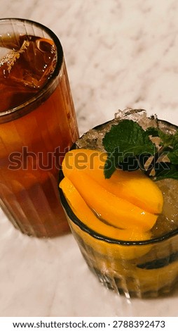 Refreshing iced tea and mango mojito drinks on marble table, tropical cafe beverage concept with cold summer refreshments and mint garnish