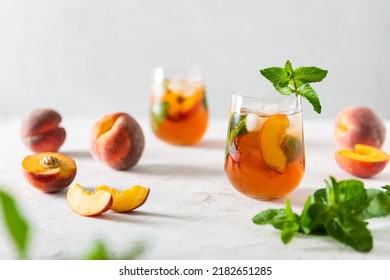 Refreshing iced tea with ripe peaches on white background. Delicious peach iced tea Cuba Libre or Long Island iced tea cocktail in glasses. Summer cold fruit drink. Bar, cafe, restaurant menu