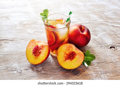 Refreshing iced tea with ripe peaches on rustic background, selective focus, toned image