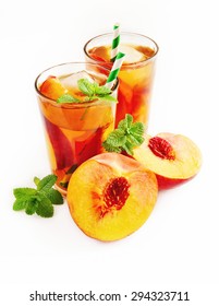 Refreshing iced tea with ripe peaches on white background, selective focus