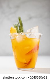 Refreshing Juicy Peach Cocktail With Ice, Rosemary, Sugar Rim, Fruit Slices In Misted Glass On White Wood Table, Concrete Wall, Vertical.