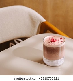 Refreshing layered raspberry chocolate drink with pink foam and dried raspberries on a cafe table