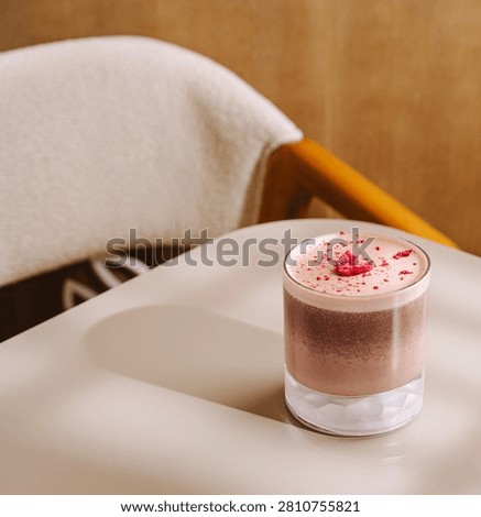 Refreshing layered raspberry chocolate drink with pink foam and dried raspberries on a cafe table