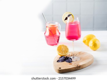 Refreshing lemonade made of red basil and lemon in a glass and in a jug. Copy space.