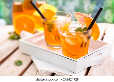Refreshing lemonade with oranges and mint on wooden table.