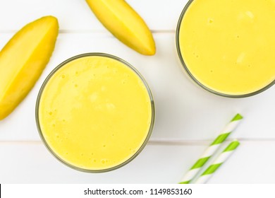 Refreshing Mango And Yogurt Smoothie In Glasses, Photographed Overhead On White Wood (Selective Focus, Focus On The Top Of The Drinks)