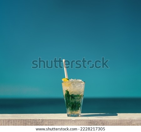 A refreshing Mojito cocktail served on a wooden table. Shot on a hot summer day in Lozenets, Bulgaria in front of a clear sky over the open sea in the background.