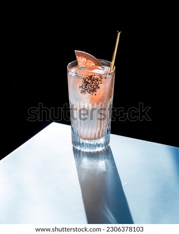 Refreshing Paloma Cocktail with Tequila and Grapefruit Soda against the light on white table and with black background
