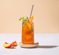 Refreshing Peach Ice And Mint Tea. Vegan Homemade Cold Summer Drink On Tall Glass On A Light Background With Fresh Fruits And Shadows. Front View And Free Space For Text.