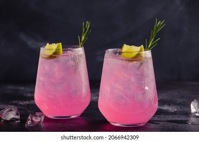 Refreshing Pink Drink Or Cocktail With Ice, Garnished With A Slice Of Lime And Rosemary.