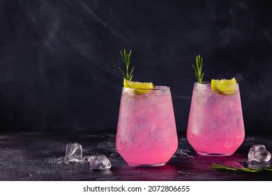 Refreshing Pink Drink Or Cocktail With Ice, Garnished With A Slice Of Lime And Rosemary.