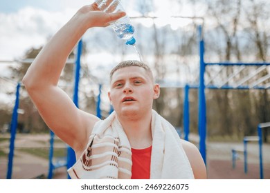 The Refreshing Pour Male Athlete Cools Down with Water Bottle. A male athlete cools down after an intense workout by pouring water from a bottle on his face, his exhausted expression - Powered by Shutterstock