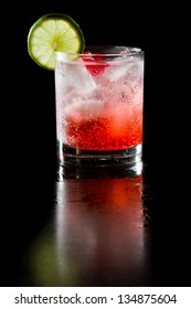 Refreshing Red Cocktail With Sparkling Water And Ice Garnished With A Lime And Cherry