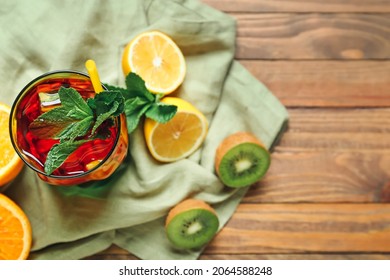 Refreshing red fruit drink with mint and citrus slices on wooden table, healthy summer beverage