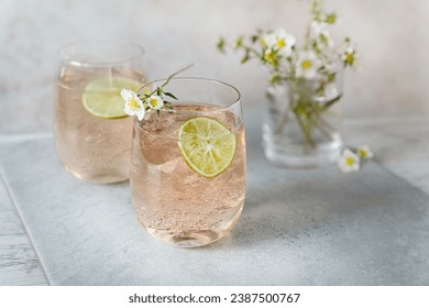 Refreshing sparkling pink cocktails in glasses served with lemon slices, ice cubes and strawberry blooms