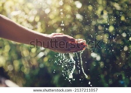Refreshing splashes. Closeup shot of a man holding his hands under a stream of water outdoors.