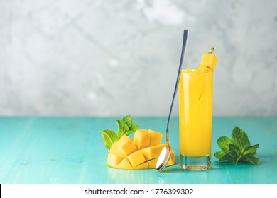 Refreshing summer cocktails made of mango, cold drink or a drink with ice on a blue gray background. Fresh summer ice cold mango cocktail or juice with mint  and mango fruit.