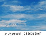 A refreshing summer day with white clouds spreading across the calm blue sky. This photo captures the natural beauty and tranquility of the moment, evoking a sense of relaxation and peace. It represen