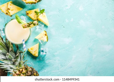 Refreshing summer drink, homemade pina colada cocktail, on a light blue background, with pieces of pineapple, coconut, ice and mint leaves, copy space top view