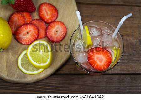Refreshing summer drink with ice, strawberries and lemon