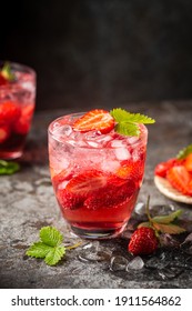 Refreshing summer drink with strawberry slices in glasses on dark background