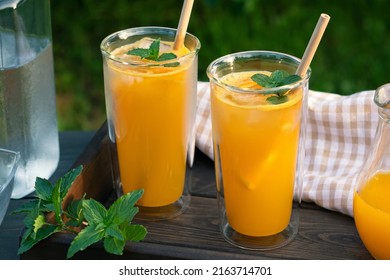 Refrescante cóctel de naranja casero de verano en vasos altos de vidrio doble con menta y hielo, enfoque selectivo