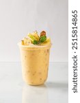 Refreshing tropical fruit smoothie topped with fresh pineapple, chia seeds, and mint leaves in a clear cup on a white background.