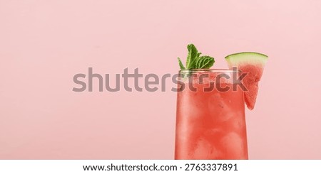 Refreshing watermelon mocktail with mint and ice stands on soft pink background, bringing playful summer party mood and feel.