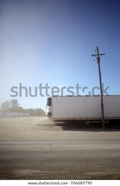 Refrigerated trailers for\
delivering cold goods parked in a large parking lot at a freight\
depot or\
distributor