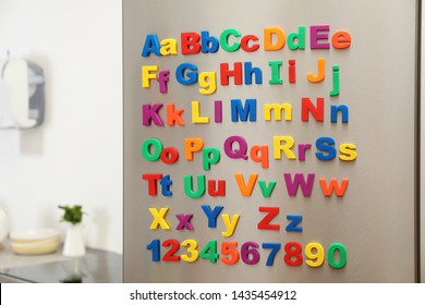 Refrigerator Door With Colorful Magnetic Letters And Numbers In Kitchen. Space For Text