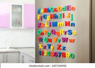 Refrigerator Door With Colorful Magnetic Letters And Numbers In Kitchen. Space For Text