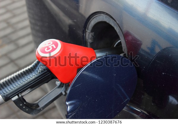 Refueling a car\
with fuel - a red refueling gun with 95 gasoline. Fuel business,\
oil, rise in price of\
gasoline