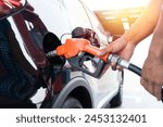Refueling the car at a gas station fuel pump. Man driver hand refilling and pumping gasoline oil the car with fuel at he refuel station. Car refueling on petrol station. Fuel pump at station.