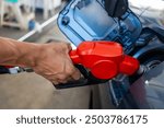 Refueling the car at a gas station fuel pump. Man driver hand refilling and pumping gasoline oil the car with fuel at the refuel station. Car refueling on petrol station. Fuel pump at the station