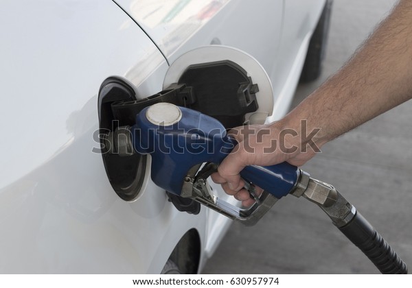Refueling car at a gas station. Car\
fuel tank and gas pump. Close-up of man hand filling\
fuel