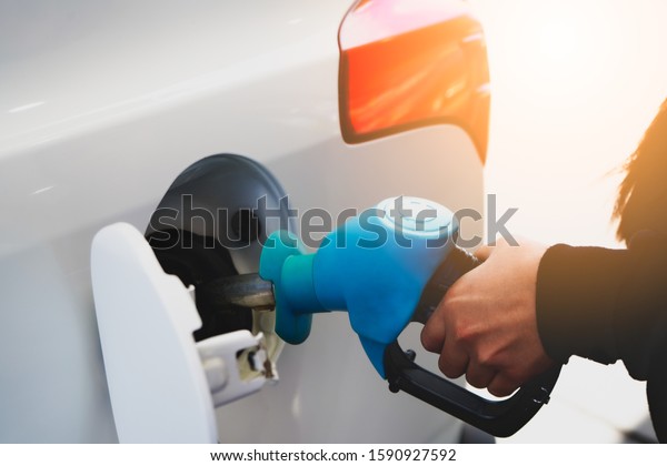 Refueling car in\
gasoline station. Woman driver hand squeeze the handle, fill the\
tank with petrol,\
self-service.