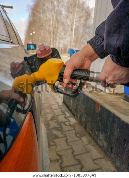 Refueling a car\
with a pistol at a gas\
station.