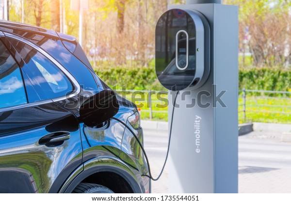 Refueling for cars e-mobility. Charging an\
electric car at hybrid engine gasoline and electricity repair shop\
service garage
