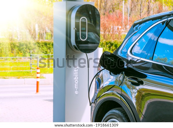Refueling for cars e-mobility. Charging an\
electric car at hybrid engine gasoline and electricity. Sunlight as\
an electric renewable energy\
concept