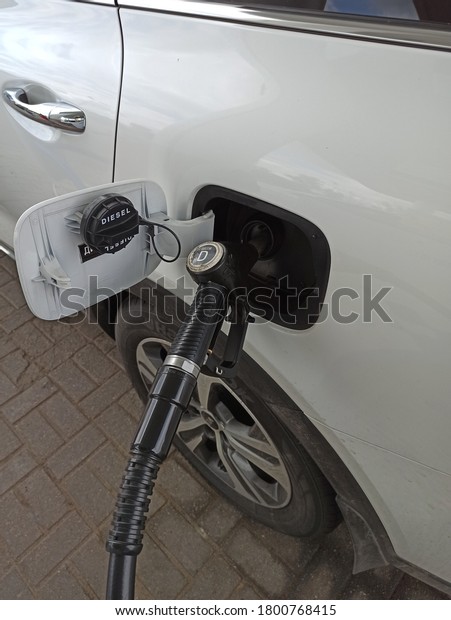 Refueling the gas tank with a gun. Refueling a\
white car at a gas station. Black\
gun