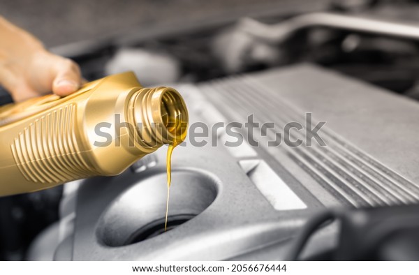 Refueling and pouring oil into car motor engine.\
Car maintenance and care\
concept.
