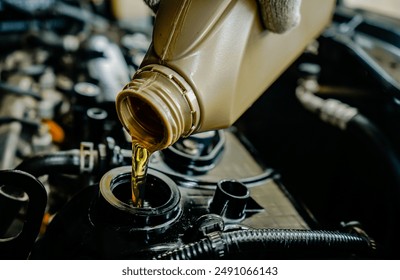 Refueling and pouring oil into the engine of the car. Close-up of changing new engine oil in a car, Car maintenance concept - Powered by Shutterstock