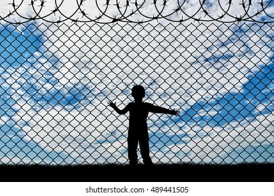 Refugee Children Concept. Child Refugee, Near The Fence Of Barbed Wire