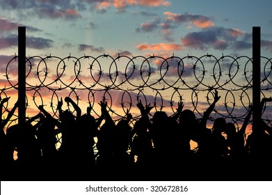 Refugee Concept. Silhouette Of Refugees Climb Over The Barbed Wire At The Border