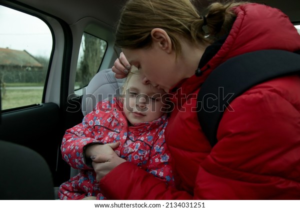 The refugees fleeing the war. Mother\
and her daughter in car. Refugees, war crisis\
concept.